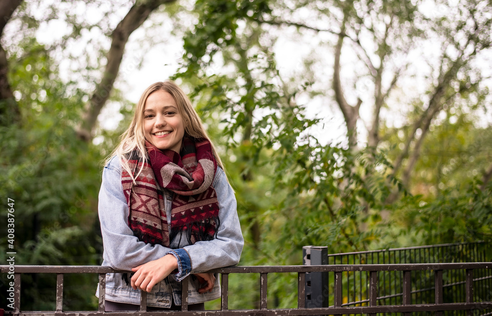 Smiling woman leaning on railing in autumnal park Smiling woman leaning on railing in autumnal park