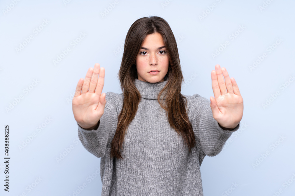 Teenager Brazilian girl over isolated blue background making stop gesture and disappointed Teenager Brazilian girl over isolated blue background making stop gesture and disappointed