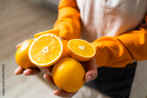 Woman holding orange and slice of orange in hand while standing at home photo