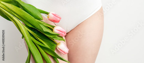 Quadro su tela Bikini area of a young woman wearing a white underwear with pink tulips on white