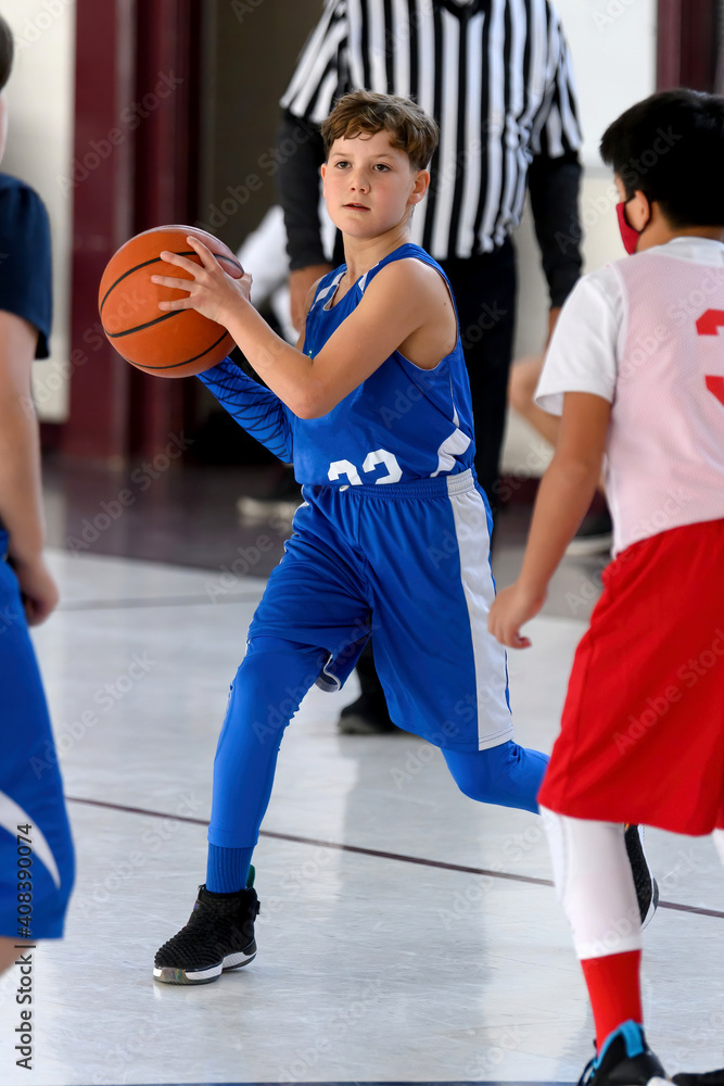 Fototapeta premium Young athletic boy playing in a game of basketball