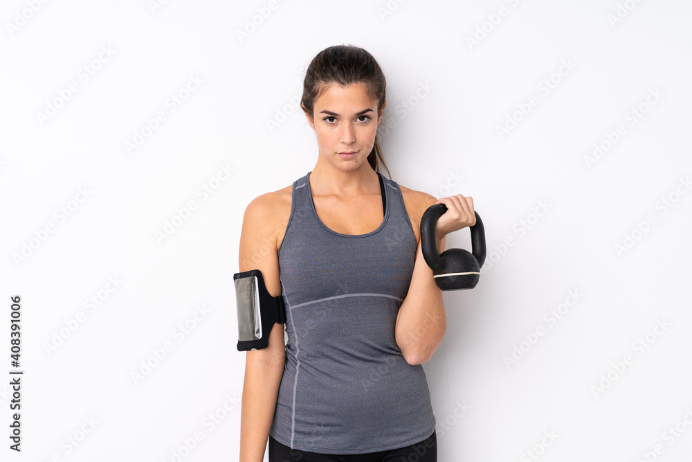 Teenager Brazilian sport girl over isolated white background making weightlifting with kettlebell Teenager Brazilian sport girl over isolated white background making weightlifting with kettlebell