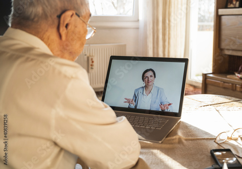 Female doctor giving advice to senior male patient during video call at home photo
