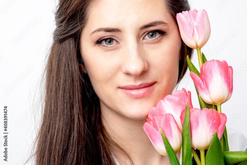 Portrait of a happy young caucasian woman with pink tulips against a white background Portrait of a happy young caucasian woman with pink tulips against a white background