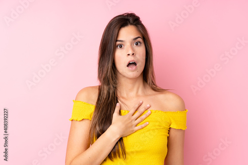 Teenager Brazilian girl over isolated pink background surprised and shocked while looking right