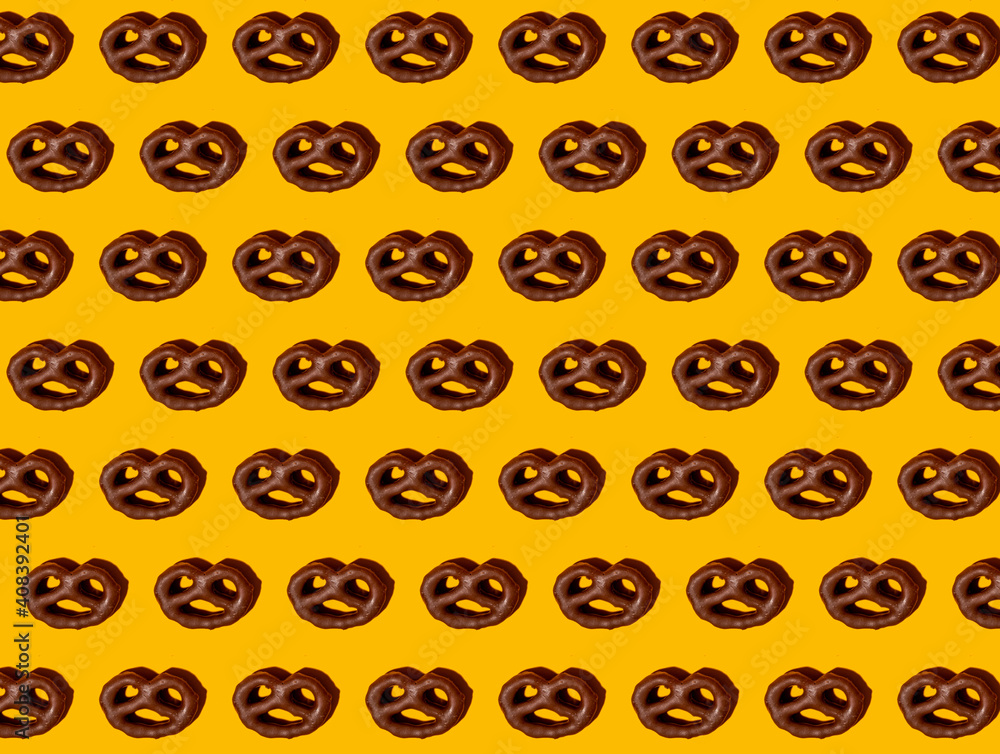 Pattern of chocolate pretzels against yellow background Pattern of chocolate pretzels against yellow background