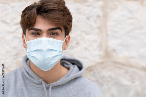 Handsome young man wearing protective face mask against wall during COVID-19 photo