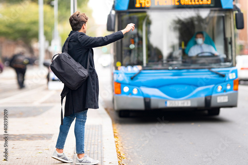 Young man hailing bus from footpath in city photo