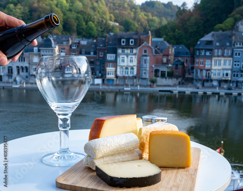 Pouring of Belgian abbey beer and tasting of cheeses made with trappist beer and fine herbs with view on Maas river in Dinant, Wallonia, Belgium photo