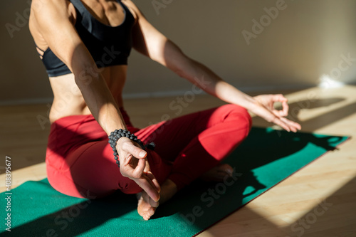 Mature woman doing sukasana meditating pose on exercise mat at home photo