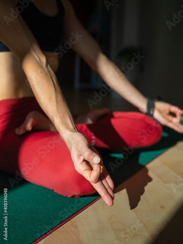 Yogini in sukhasana position on exercise mat at home in sunlight photo