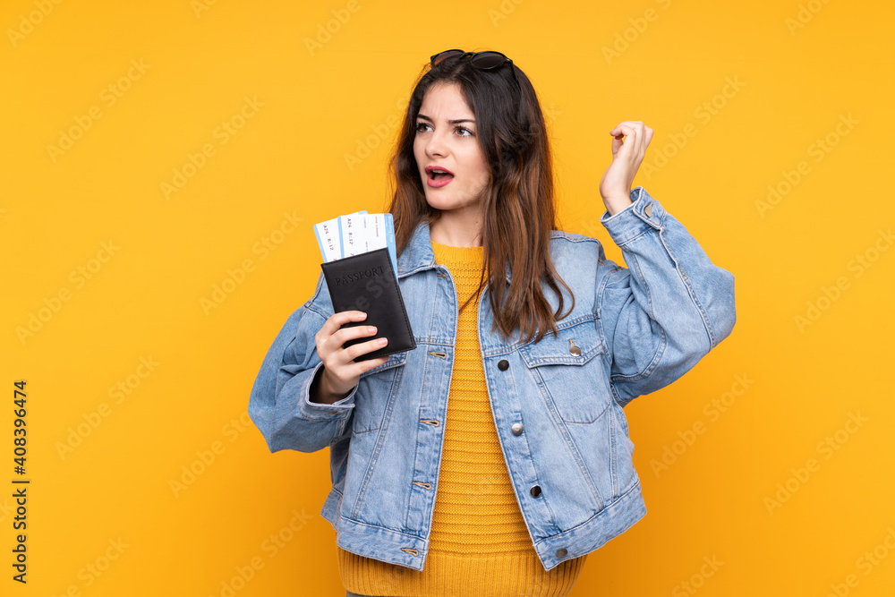 Young caucasian woman isolated on yellow background in vacation with plane tickets and surprised Young caucasian woman isolated on yellow background in vacation with plane tickets and surprised