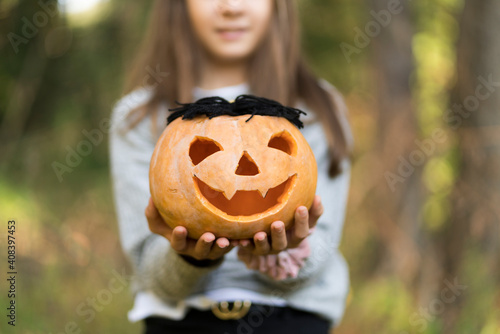 Girl holding Halloween pumpkin while standing at park photo