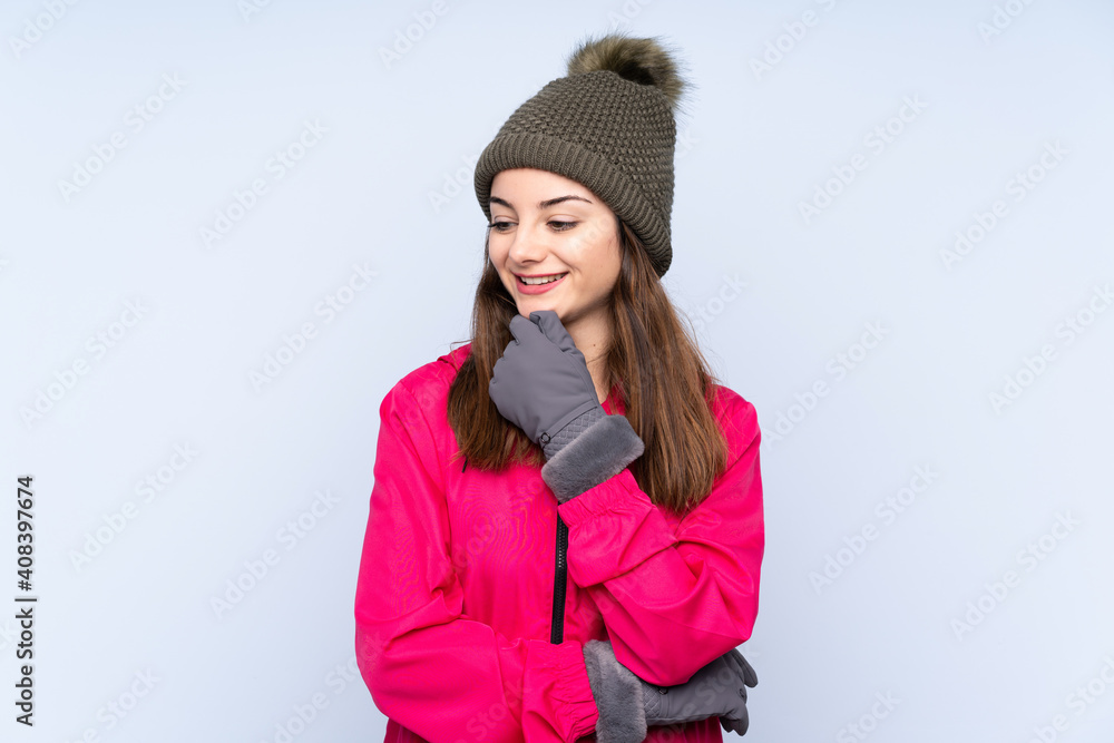Young girl with winter hat isolated on blue background looking to the side Young girl with winter hat isolated on blue background looking to the side