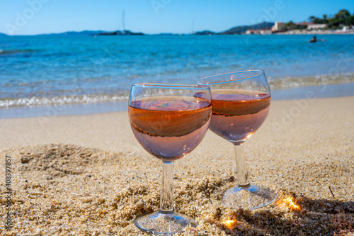 Two glasses of local rose wine on white sandy beach and blue Mediterranean sea on background, near Le Lavandou, Provence, France photo