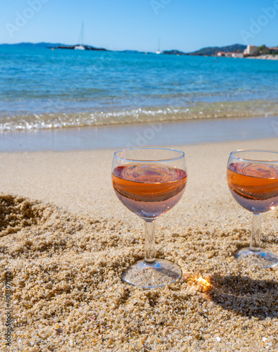 Two glasses of local rose wine on white sandy beach and blue Mediterranean sea on background, near Le Lavandou, Provence, France