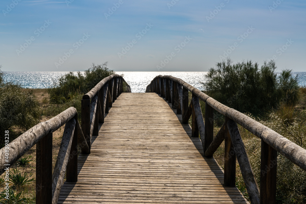 Fototapeta premium long wooden boardwalk and beach access leads to beach and glistening ocean