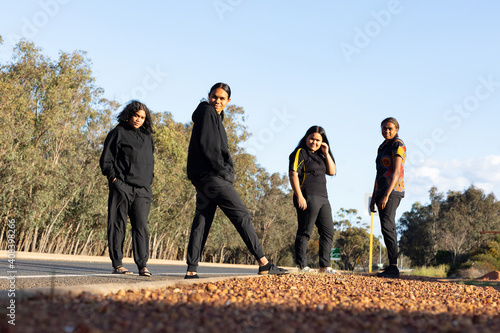 four teenagers dressed in black standing on the edge of a road photo