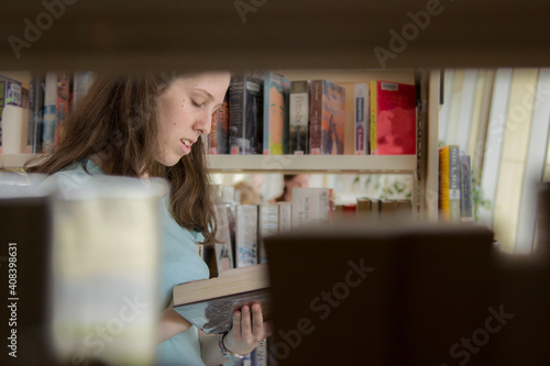 Young lady choosing a book to read from the local library photo