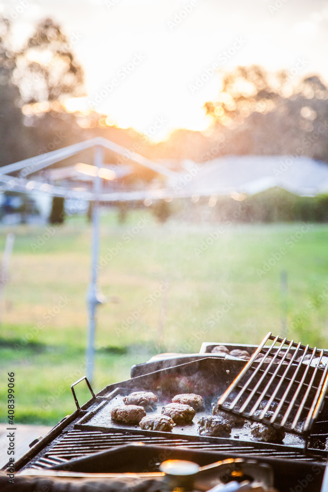 Rissoles cooking on a BBQ in the backyard at sunset Rissoles cooking on a BBQ in the backyard at sunset