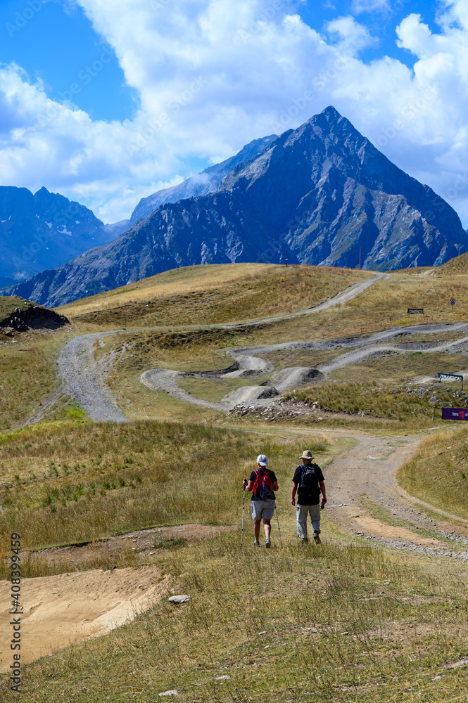 Old man and woman hiking in Ecrins alpine mountain range in summer, Les deux Alpes, France