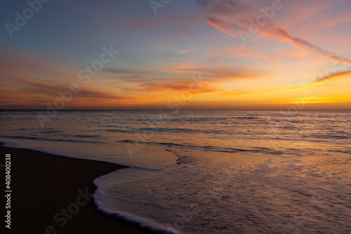 gorgeous colorful sunset over the ocean and beach with gentle waves lapping at the shore