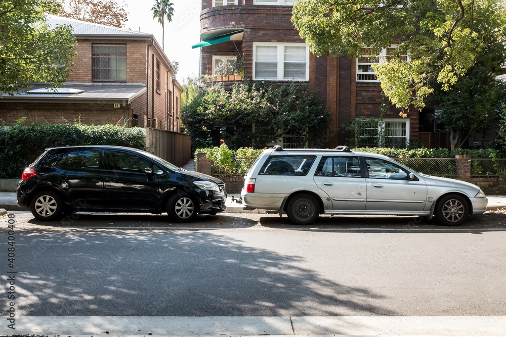 old and new car parked in a suburban street old and new car parked in a suburban street