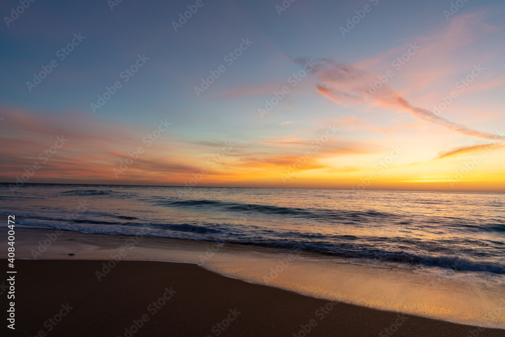 gorgeous colorful sunset over the ocean and beach with gentle waves lapping at the shore