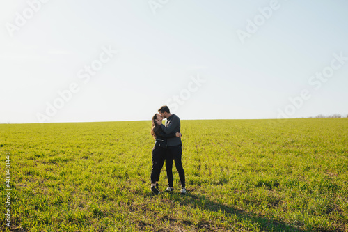 Couple kissing over natural green background. They standing on green field and hugging. Copy space. © eduard