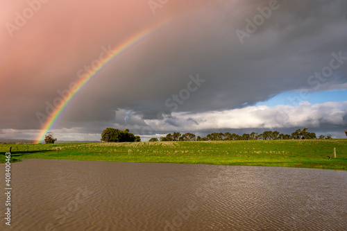 A vivid rainbow arching over a dam on farmland