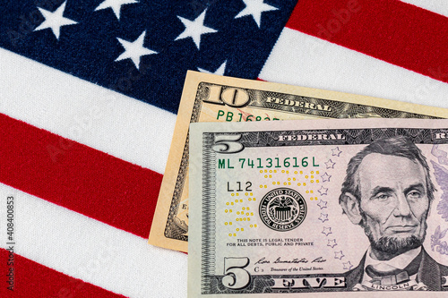 Closeup of ten and five dollar bills with American flag.  Concept of 15 dollar federal minimum wage increase photo