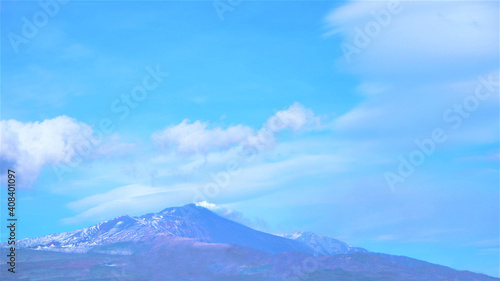 The mount Etna Volcano with smoke and clouds in winter.