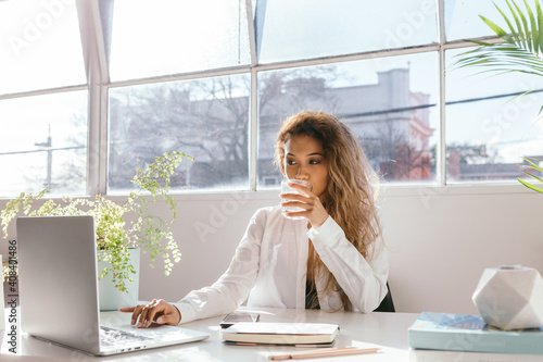 Female sipping water while working in a bright clinical white office photo
