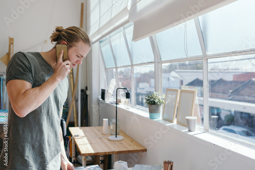 Man in his 20s on the phone in a creative studio office photo