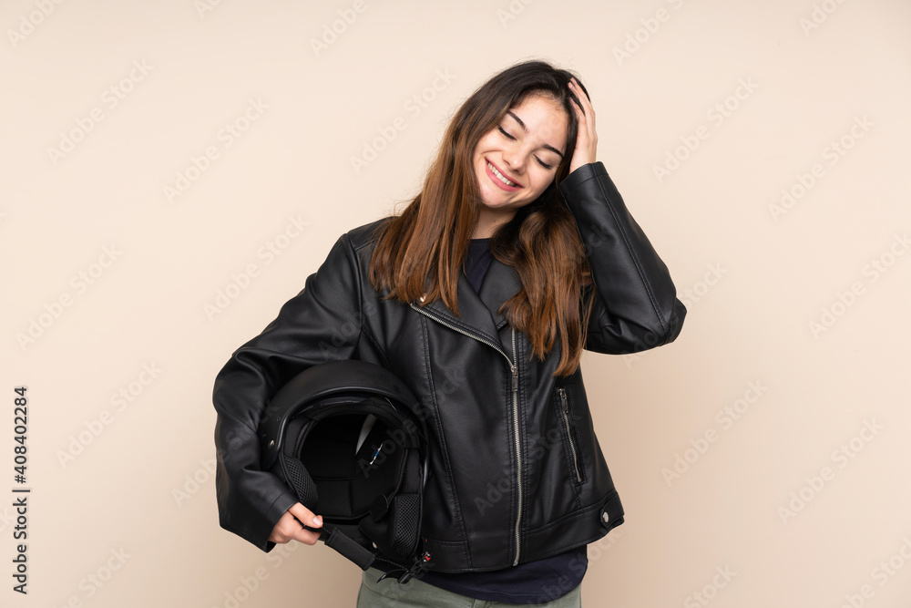 Woman with a motorcycle helmet isolated on beige background laughing Woman with a motorcycle helmet isolated on beige background laughing