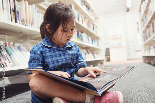 Young student girl reading in library