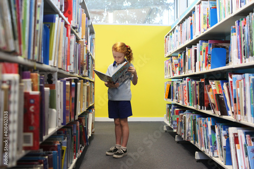 Girl reading a book in a library photo