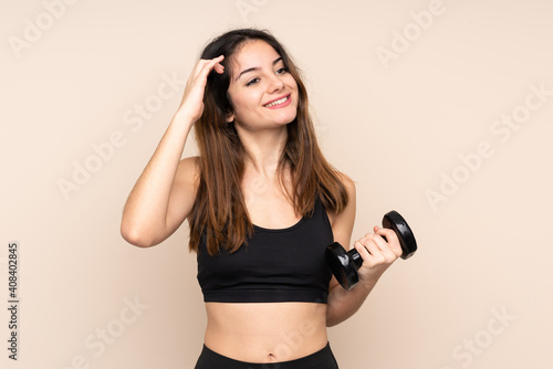 Young sport woman making weightlifting isolated on beige background laughing
