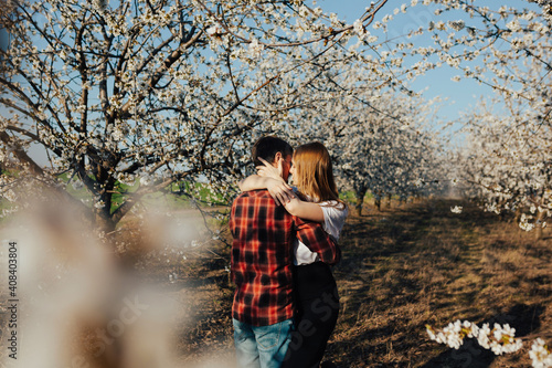 Couple in love hugging near blossoming trees in the garden. Passion and love concept.