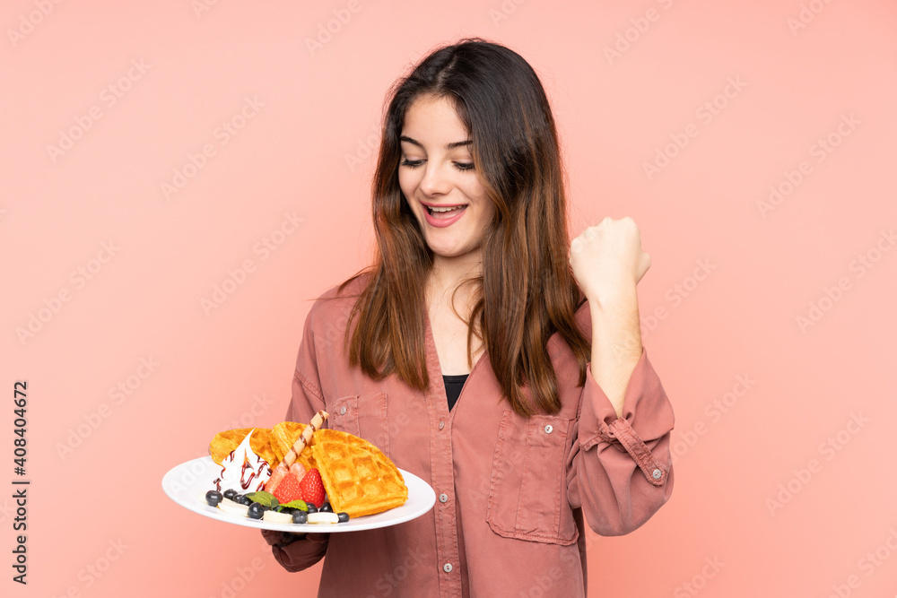 Young caucasian woman holding waffles isolated on pink background celebrating a victory Young caucasian woman holding waffles isolated on pink background celebrating a victory