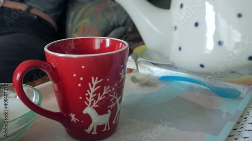 Pouring hot tea in a red cup with a teapot
