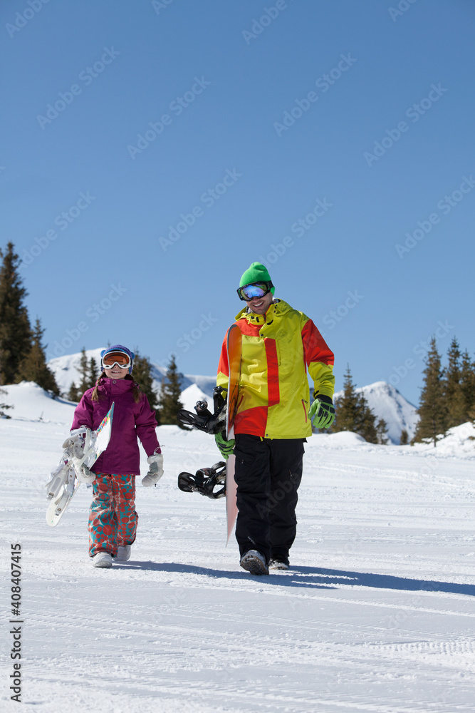 USA, Colorado, Telluride, Father and daughter (10-11) walking with snowboards in winter scenery USA, Colorado, Telluride, Father and daughter (10-11) walking with snowboards in winter scenery