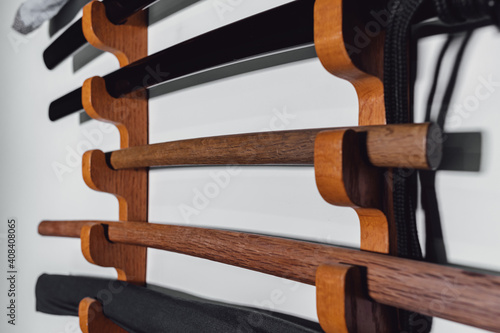 Special stand on the white wall for training swords made of oak wood and iron. Traditional Japanese training weapons for different martial arts disciplines. photo