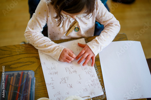 Above-view of a small child sitting at a table writing a story