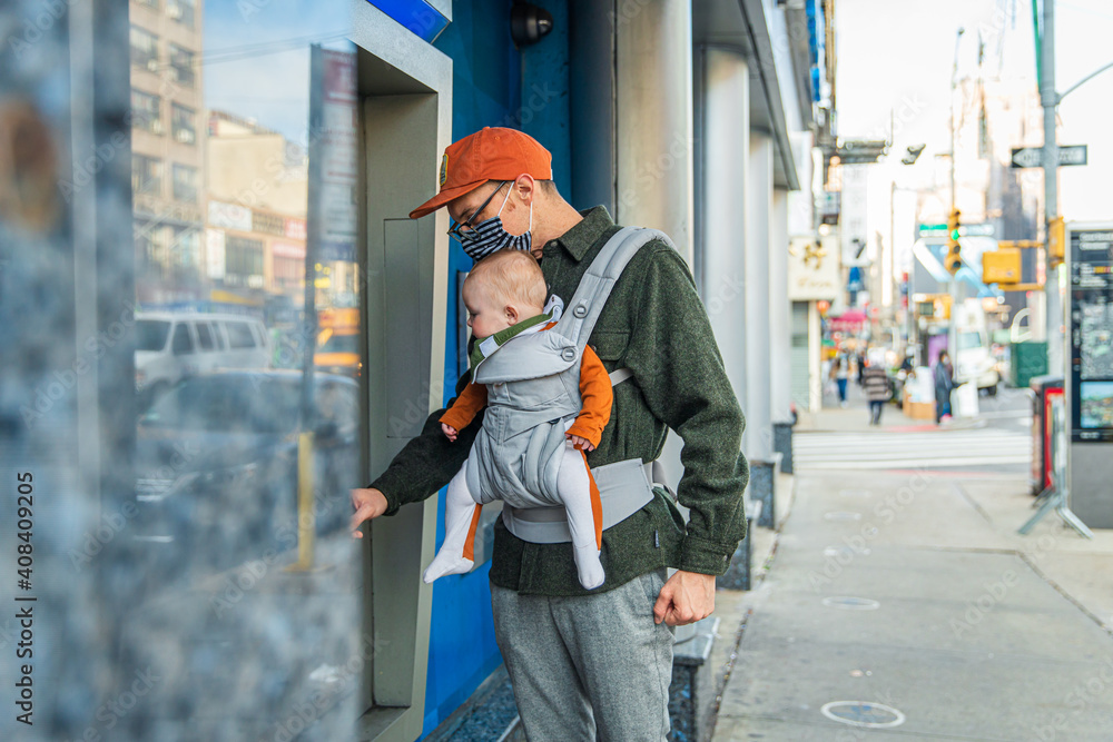 Father with baby daughter using ATM at sidewalk in city during COVID-19 Father with baby daughter using ATM at sidewalk in city during COVID-19