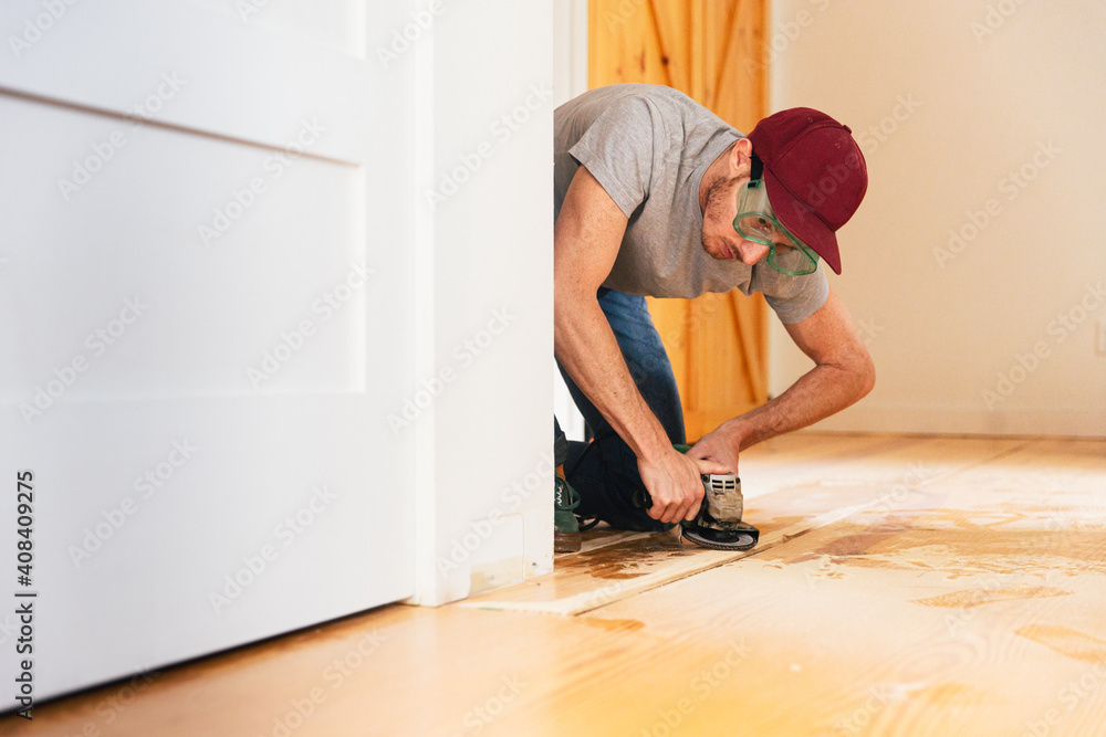 Mid adult man installing hardwood floor at home Mid adult man installing hardwood floor at home