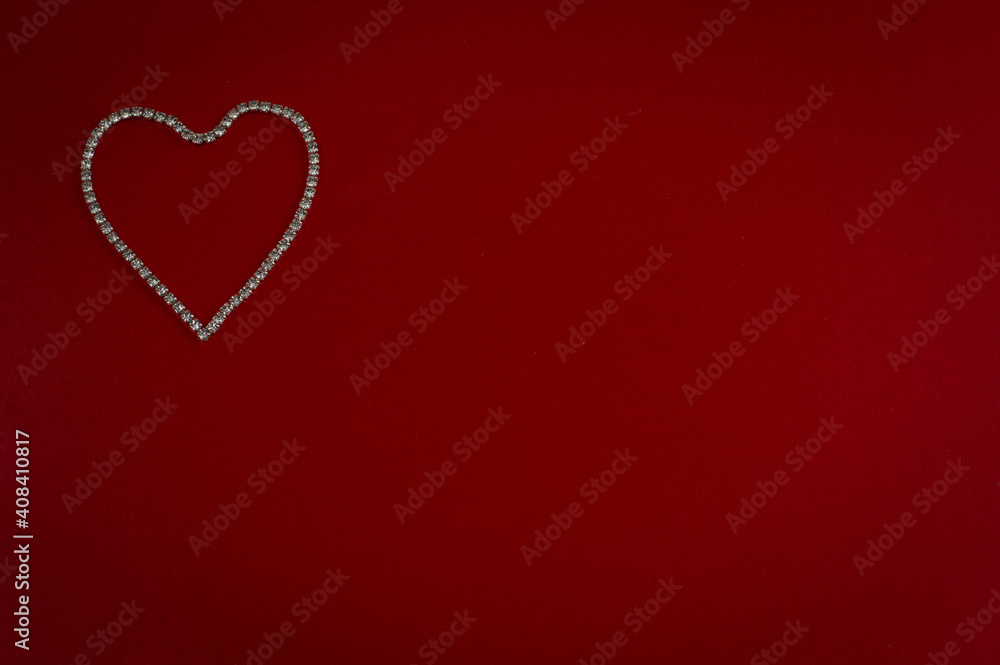 A heart made of rhinestones is placed on a bright red background.