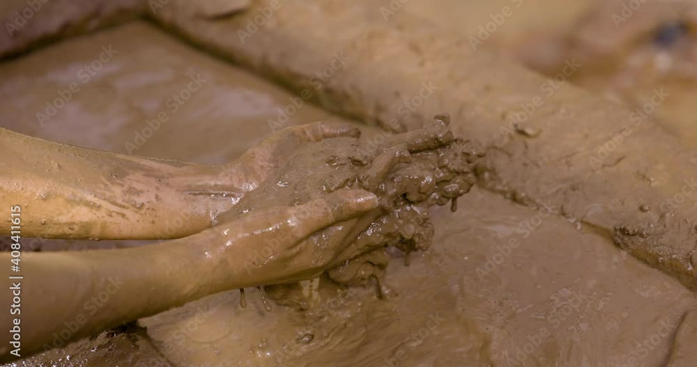 A woman smears her skin with therapeutic cosmetic mud and clay from a natural lake. Cleaning face and body skin with spa cleansing mud. Skincare beauty treatment. A woman smears her skin with therapeutic cosmetic mud and clay from a natural lake. Cleaning face and body skin with spa cleansing mud. Skincare beauty treatment.