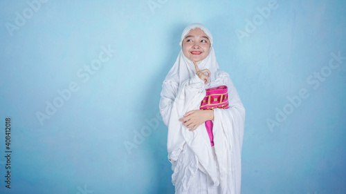 asian woman wearing muslim hijab scarf mukena thinking, imagination, question, having idea isolated on blue background in studio. ramadan concept photo