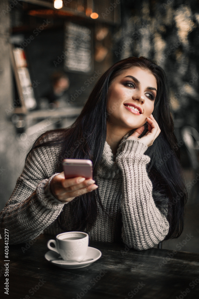 Woman using phone and drinking coffee in a cafe. Woman using phone and drinking coffee in a cafe.